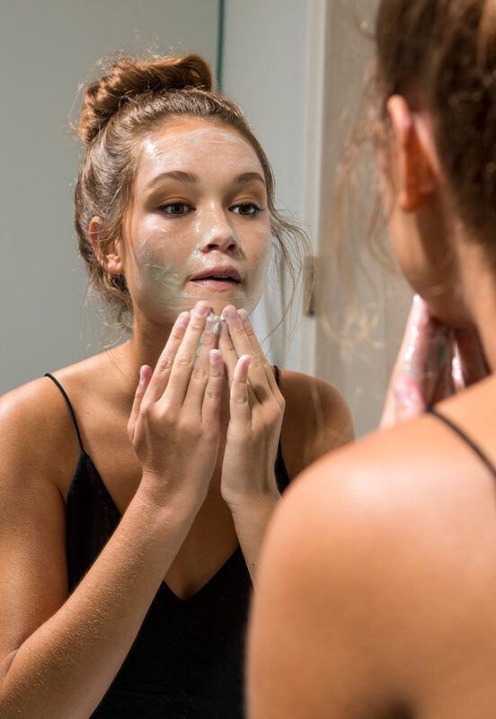  woman washing her face in front of the mirror